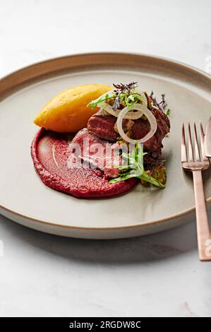 Filet d'agneau, purée de patate douce, romesco de prune de sang, oignon blanc mariné, salsa aux olives vertes et à la coriandre Banque D'Images