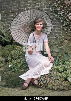 Une jeune femme dans un jardin avec un parasol. Banque D'Images