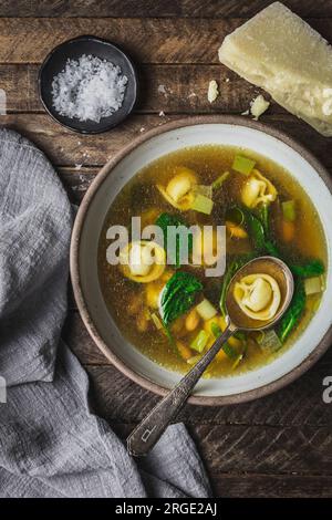 Tortellini, épinards et bouillon de poulet dans un bol avec fromage parmesan et serviette Banque D'Images