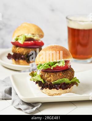 Deux hamburgers végétaliens sur des assiettes blanches avec de la bière Banque D'Images