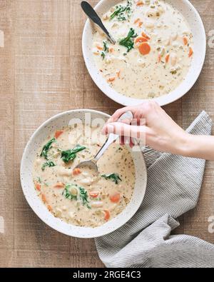 Deux bols de soupe gnocchi crémeuse végétalienne avec cuillère à main femelle Banque D'Images