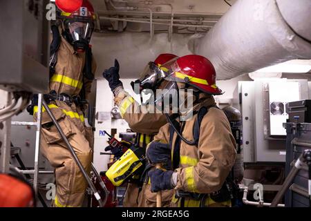 230805-N-LK647-1082 MER IONIENNE (5 août 2023) de la droite: technicien cryptologique (Collection) Vincent Turner, 3e classe, affecté au croiseur de missiles guidés de classe Ticonderoga USS Normandy (CG 60), le pompier Jaylen Koch et le pompier Jeffery Camacho de Damage entrent dans la salle principale des machines 1 pour combattre un tir simulé alors que le navire effectue un exercice général de quart, le 5 août 2023. Les forces du Groupe maritime permanent de l'OTAN 2 (SNMG 2) et du Gerald R. Ford Carrier Strike Group (GRFCSG) mènent la série d'événements d'entraînement maritime haut de gamme Sage Wolverine en Méditerranée centrale à In Banque D'Images