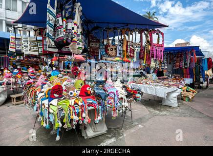 Une exposition colorée de chullos, de bonnets et de sacs à bandoulière à vendre dans un étal du marché indien à Otavalo en Équateur. Banque D'Images