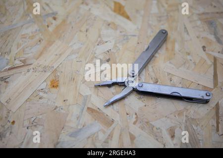 Couteau de poche argenté tout usage sur un fond en bois rustique. Couteau pliant vue de dessus avec outils Banque D'Images