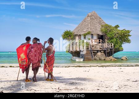 Masai hommes sur la plage, le Rock Restaurant en arrière-plan, Pingwe, Zanzibar, Tanzanie, Afrique de l'est Banque D'Images