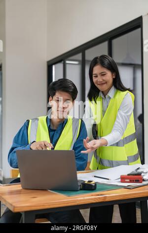 Deux jeunes hommes et femmes ingénieurs se réunissent, travaillent, discutent, planifient, conçoivent, mesure de la disposition des plans de construction dans le plancher du chantier Banque D'Images
