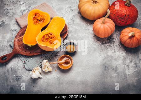 Moitiés de courge butternut bio crue avec épices et ingrédients pour la cuisson Banque D'Images