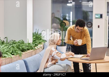 Portrait vue de côté de femme moderne du Moyen-Orient portant la couverture de la tête dans le bureau et consultant avec un collègue masculin, espace de copie Banque D'Images