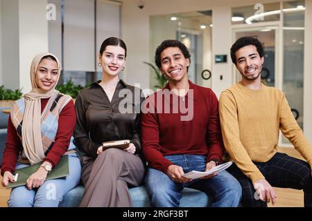 Portrait vue de face de la jeune équipe d'affaires du Moyen-Orient posant dans un bureau moderne tout en regardant la caméra et souriant Banque D'Images