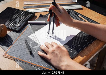 Architecte et concepteur travaillant avec précision sur un projet de dessin d'esquisses et de brouillons techniques sur papier en utilisant des outils professionnels comme les règles compas et Banque D'Images