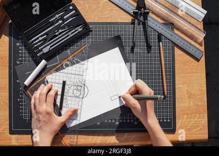 Architecte et concepteur travaillant avec précision sur un projet de dessin d'esquisses et de brouillons techniques sur papier en utilisant des outils professionnels comme les règles compas et Banque D'Images