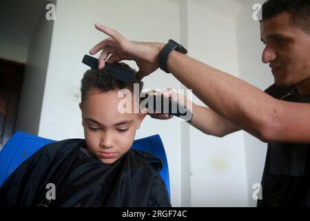 salvador, bahia, brésil - 27 août 2022: barber utilise une machine pour couper les cheveux d'un enfant dans la ville de Salvador. Banque D'Images