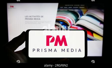 Personne tenant un smartphone avec le logo de la maison d'édition française Prisma Media sur l'écran devant le site Web. Concentrez-vous sur l'affichage du téléphone. Banque D'Images