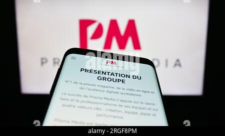 Téléphone portable avec site Internet de la maison d'édition française Prisma Media à l'écran devant le logo de l'entreprise. Effectuez le focus sur le coin supérieur gauche de l'écran du téléphone. Banque D'Images