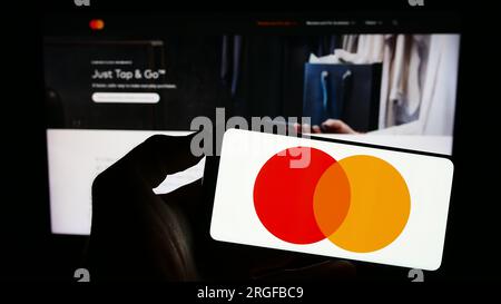 Personne détenant le téléphone cellulaire avec le logo de la société de paiement américaine Mastercard Inc. Sur l'écran devant la page Web de l'entreprise. Concentrez-vous sur l'affichage du téléphone. Banque D'Images