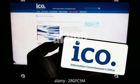 Personne tenant un smartphone avec le logo du British information Commissioner's Office (ICO) sur l'écran devant le site Web. Concentrez-vous sur l'affichage du téléphone. Banque D'Images