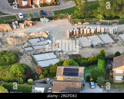 Vue aérienne regardant sur une zone de construction de logements neufs sur le bord des maisons existantes et des champs verts Banque D'Images