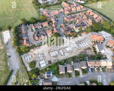 Vue aérienne regardant sur une zone de construction de logements neufs sur le bord des maisons existantes et des champs verts Banque D'Images