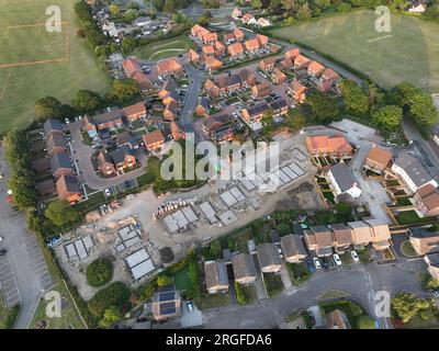 Vue aérienne regardant sur une zone de construction de logements neufs sur le bord des maisons existantes et des champs verts Banque D'Images