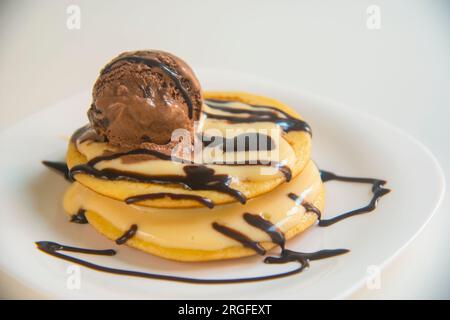 Glace au chocolat sur les crêpes avec la crème et le sirop de chocolat. Banque D'Images