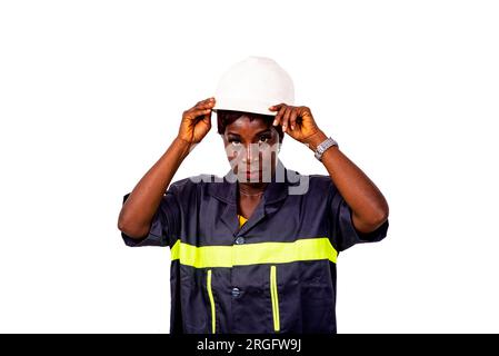 portrait d'une belle ingénieure portant un uniforme de travail et un casque de sécurité blanc. Banque D'Images