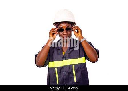 portrait d'une belle ingénieure portant un uniforme de travail et un casque de sécurité blanc et des lunettes de soleil. Banque D'Images