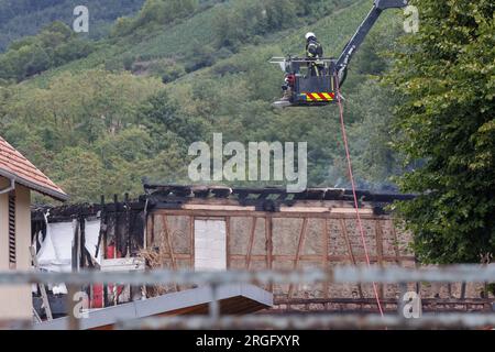 Wintzenheim, France. 09 août 2023. Un pompier sur une échelle tournante regarde le lieu de l'accident. Après un incendie dans une maison de vacances, la police française pense que neuf personnes sont mortes jusqu'à présent. L'incendie s'est déclaré vers 6:30 heures du matin dans une maison de vacances qui avait accueilli deux groupes d'adultes handicapés ayant une déficience mentale légère qui avaient voyagé de Nancy. Crédit : Philipp von Ditfurth/dpa/Alamy Live News Banque D'Images