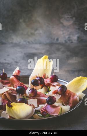 Melon doux enveloppé de jambon, apéritif italien, sur fond rustique gris, vertical avec espace de copie Banque D'Images