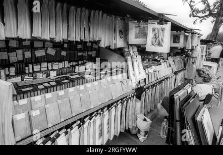 Photographie en noir et blanc des archives des années 1990 de bouquiniste vendant des livres d'occasion et des estampes d'une boîte verte traditionnelle sur la rive gauche de la Seine à Paris. Ils sont un site du patrimoine mondial de l'UNESCO. Banque D'Images