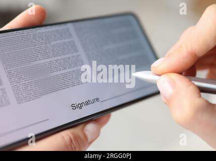 Personne place la signature avec le stylet sur l'écran du contrat du smartphone Banque D'Images