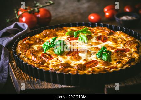 Quiche de tomate entière au basilic sur fond en bois, gros plan Banque D'Images