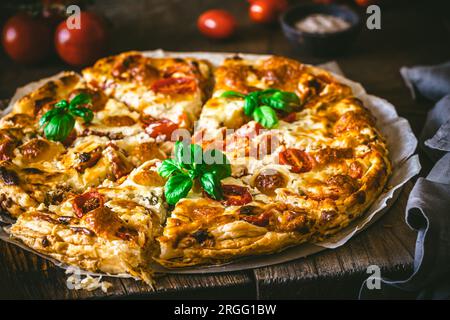 Quiche de tomate entière au basilic sur fond en bois, gros plan Banque D'Images