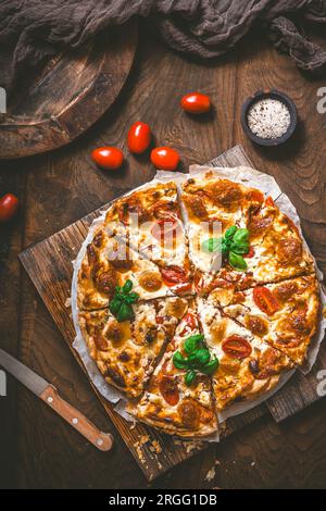 Quiche de tomate entière avec basilic sur fond en bois, vue de dessus Banque D'Images