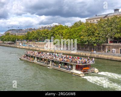 Touristes et touristes naviguant le long de la Seine dans le centre de Paris à bord du bateau mouche Jeanne Moreau. Banque D'Images