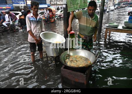 Dhaka, Bangladesh. 09 août 2023. Un vendeur fabrique de la nourriture pour la vente dans les rues de l'exploitation des forêts d'eau à Dhaka, au Bangladesh, le 9 août 2023. Les fortes pluies de mousson ont provoqué une engorgement extrême des eaux dans la plupart des zones de la ville de Dhaka, au Bangladesh. Les routes étaient submergées rendant les déplacements lents et dangereux. Crédit : Mamunur Rashid/Alamy Live News Banque D'Images