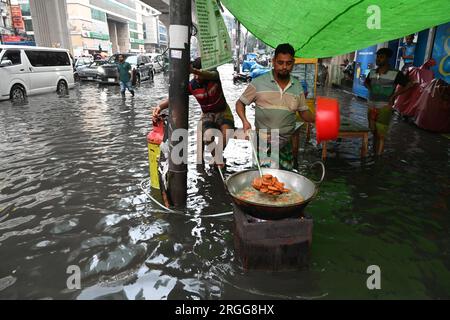 Dhaka, Bangladesh. 09 août 2023. Un vendeur fabrique de la nourriture pour la vente dans les rues de l'exploitation des forêts d'eau à Dhaka, au Bangladesh, le 9 août 2023. Les fortes pluies de mousson ont provoqué une engorgement extrême des eaux dans la plupart des zones de la ville de Dhaka, au Bangladesh. Les routes étaient submergées rendant les déplacements lents et dangereux. Crédit : Mamunur Rashid/Alamy Live News Banque D'Images