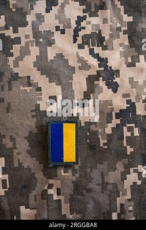 Photo de la bannière du drapeau ukrainien sur le textile de camouflage avec des couleurs de pixel militaire. Banque D'Images