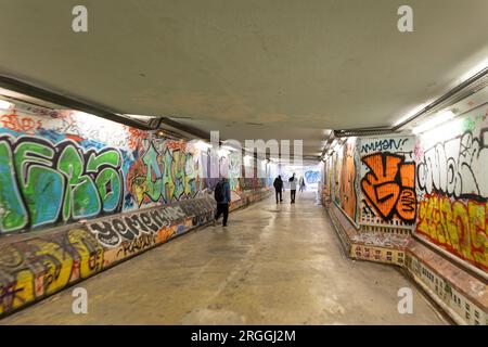 21 février 2023 Lisbonne, Portugal : les gens marchent à travers un passage souterrain avec des murs peints de graffitis Banque D'Images