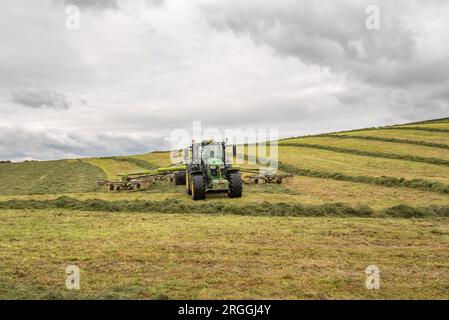 Tracteur ramant pendant la fabrication de l'ensilage à Little Newton long Preston, près de Hellifield, Yorkshire Dales pendant une brève fenêtre météorologique, Banque D'Images