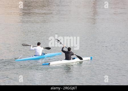 Deux gars ramer dans un canoë à la marina Banque D'Images