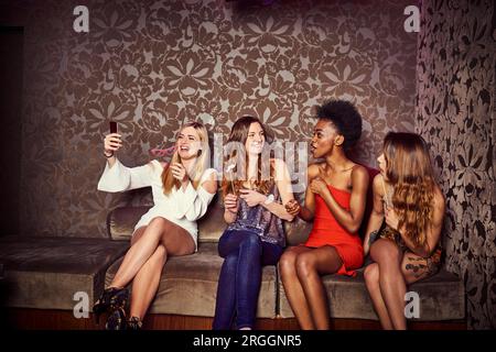 Les amis de prendre le canapé à discothèque selfies Banque D'Images