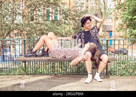 Teenage girl lying in boyfriend's lap à park Banque D'Images