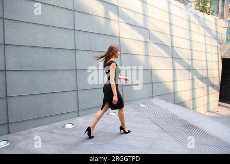 Jeune femme en robe noire walking Banque D'Images