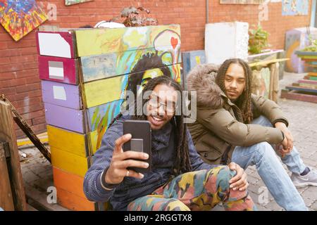 Jeune homme en tenant avec ami selfies Banque D'Images