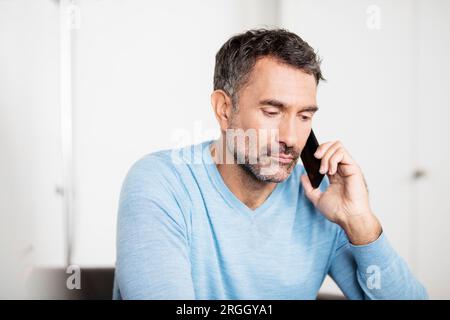 Mature businessman talking on smartphone in office Banque D'Images