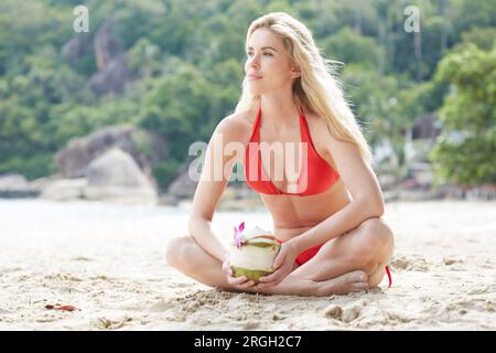 Jeune femme tenant un verre de noix de coco sur la plage Banque D'Images