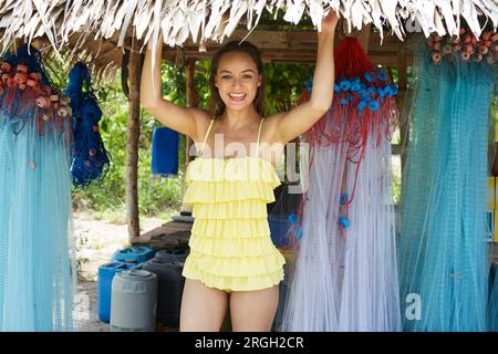 Jeune femme en cabane de plage avec des filets de pêche Banque D'Images