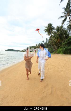 Jeune couple flying kite on beach Banque D'Images