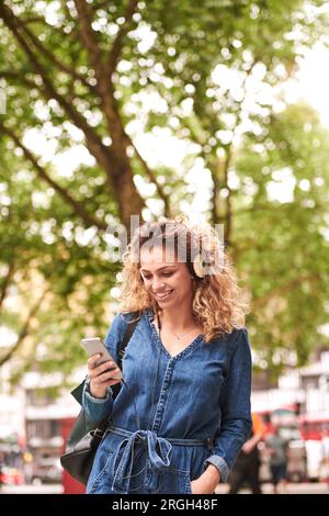 Young woman holding smart phone wearing headphones Banque D'Images