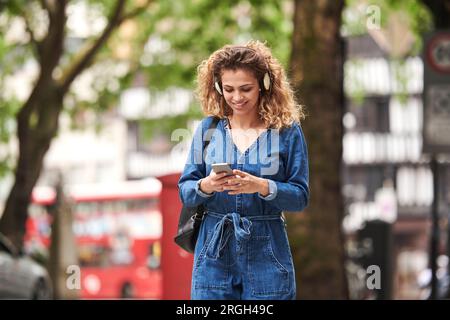 Young woman holding smart phone wearing headphones Banque D'Images